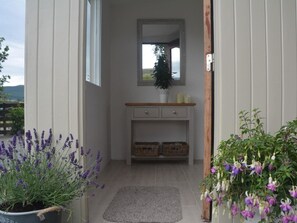 A hallway with a wooden bench, a mirror, and a potted plant. - 1 Bed in West Linton (oc-62990) (West Linton)
