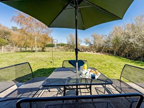An outdoor patio with a table and chairs, an umbrella, and a plate of food. - 2 Bed in Brighton (oc-80378) (Poynings)