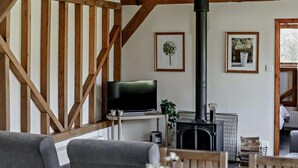 A cozy living room with a fireplace, wooden beams, a television, and framed pictures on the wall. - 2 Bed in Brighton (oc-80378) (Poynings)