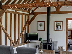 A cozy living room with a fireplace, wooden beams, a television, and framed pictures on the wall. - 2 Bed in Brighton (oc-80378) (Poynings)