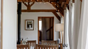 A dining area with wooden chairs and a table, string lights overhead, and a lamp on the table. - 2 Bed in Brighton (oc-80378) (Poynings)