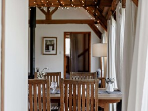 A dining area with wooden chairs and a table, string lights overhead, and a lamp on the table. - 2 Bed in Brighton (oc-80378) (Poynings)