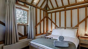 A bedroom with a wooden ceiling, a bed with white bedding, a bedside table with a lamp, and a window with curtains. - 2 Bed in Brighton (oc-80378) (Poynings)