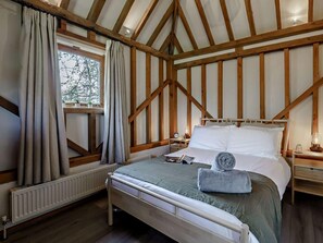 A bedroom with a wooden ceiling, a bed with white bedding, a bedside table with a lamp, and a window with curtains. - 2 Bed in Brighton (oc-80378) (Poynings)