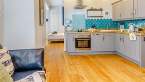 A modern kitchen with grey cabinets, a central island, and a built-in oven. - 1 Bed in Tenby (oc-85705) (Tenby)