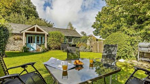 A glass table with a croissant, juice, and a menu in a sunny outdoor setting. - 3 Bed in Launceston (oc-89030) (Egloskerry)
