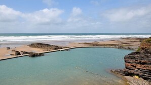 A coastal landscape with a clear sky, a beach, and a rocky pool. - 3 Bed in Launceston (oc-89030) (Egloskerry)