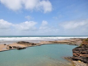 Eine Küstenlandschaft mit blauem Himmel, einem Strand und einer felsigen Lagune.