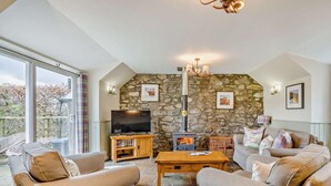 A cozy living room with stone walls, a fireplace, a television, and comfortable seating. - 2 Bed in Blairgowrie (oc-92113) (Blacklunans)