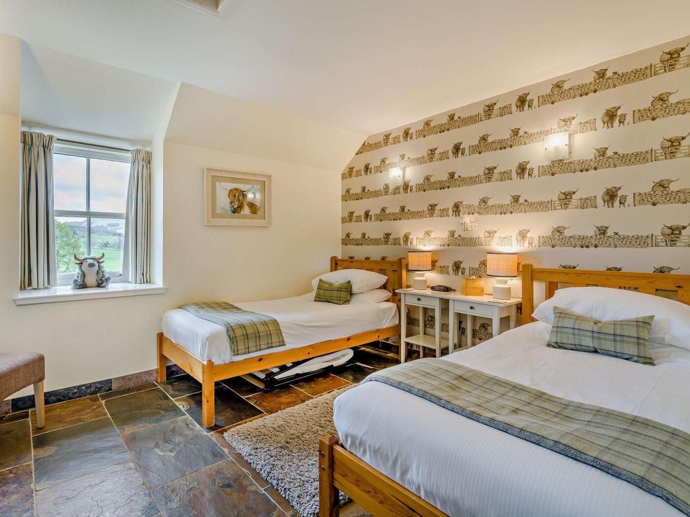 Ein Zimmer mit zwei hölzernen Betten, einem kleinen Tisch, einem Stuhl, einem Fenster mit Vorhängen und einer Wand mit einem gemusterten Design.