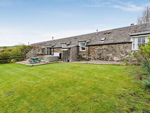 A stone building with a grassy yard and a wooden deck. - 2 Bed in Blairgowrie (oc-92113) (Blacklunans)