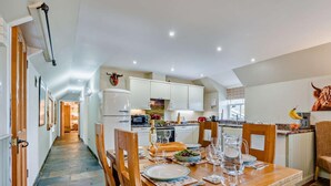 A spacious kitchen with modern appliances, a dining area with a wooden table set for two, and a view of the adjacent living area. - 2 Bed in Blairgowrie (oc-92113) (Blacklunans)