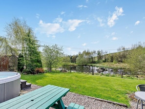 A backyard with a hot tub, picnic table, and a pond. - 2 Bed in Blairgowrie (oc-92112) (Blacklunans)