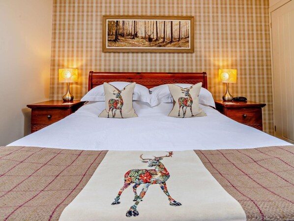 Ein Hotelzimmer mit einem großen Bett, zwei Nachttischen, einem Bild an der Wand und einem gemusterten Teppich.
