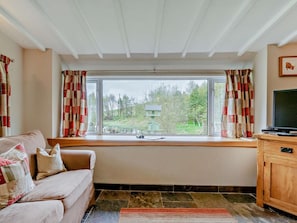 A cozy living room with a sofa, a television, and a window with curtains. - 2 Bed in Blairgowrie (oc-92112) (Blacklunans)