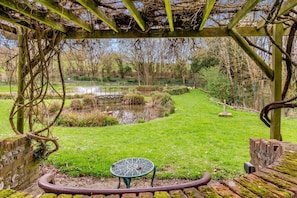 A garden with a pond, a wooden pergola, and a metal table. - 1 Bed in Milton Abbas (oc-a35016) (Milton Abbas)