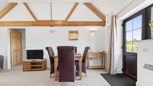 Um quarto com teto de madeira, uma mesa de jantar com cadeiras, uma televisão e uma porta que dá para o exterior.