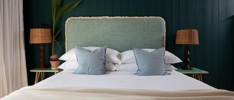 A bed with a headboard, two nightstands, a lamp, and a plant.