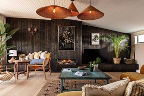 A cozy living room with a fireplace, wooden walls, and a comfortable seating area. - 4 Bed in Watergate Bay (oc-b584453) (Tregurrian)