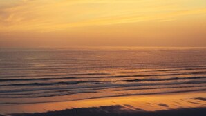 En strandscene med bølger og en solnedgang.