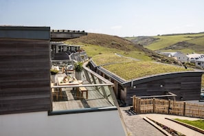 A modern outdoor dining area with a view of the countryside. - 4 Bed in Watergate Bay (oc-b584453) (Tregurrian)