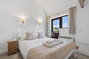 A bedroom with a bed, bedside tables, a window with curtains, and a radiator. - 1 Bed in Milton Abbas (oc-c35017) (Milton Abbas)