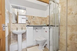 Une salle de bain équipée d’un lavabo, de toilettes et d’une douche à parois en verre.