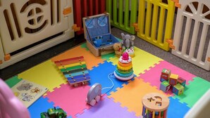 Uma área de recreação com tapete, brinquedos e um baú de brinquedos.