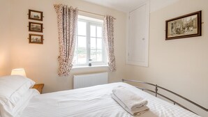 A hotel room with a bed, a window with curtains, a radiator, and framed pictures on the wall. - 3 Bed in Whitby (oc-c40269) (Whitby)