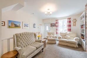 A living room with a large tufted sofa, a smaller sofa, a chair, and a bookshelf. - 3 Bed in Whitby (oc-c40269) (Whitby)