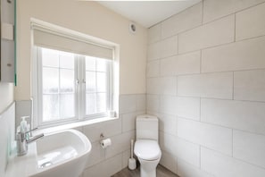 A bathroom with a white sink, toilet, and window. - 3 Bed in Whitby (oc-c40269) (Whitby)