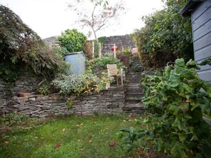 Eine steine Mauer mit einem Holzstuhl und einem kleinen Gartenhaus.