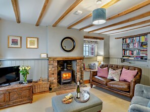 Ein gemütliches Wohnzimmer mit Kamin, Ledersofa, Fernseher und Bücherregal.