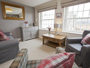 A living room with grey sofas, a wooden coffee table, a grey cabinet, and a large window with curtains. - 2 Bed in Whitby (oc-g0130) (Whitby)