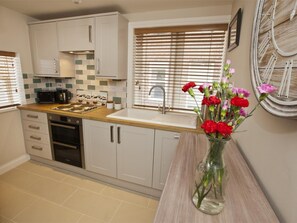A modern kitchen with white cabinets, a wooden countertop, a built-in oven, a sink, and a window with blinds. - 2 Bed in Whitby (oc-g0130) (Whitby)