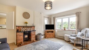 A living room with a fireplace, a television, and a sofa. - 3 Bed in Guist (oc-h33647) (Guist)