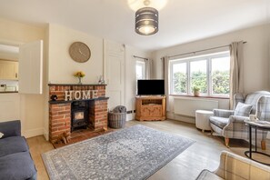 Ein Wohnzimmer mit Kamin, Fernseher und einer Couch.