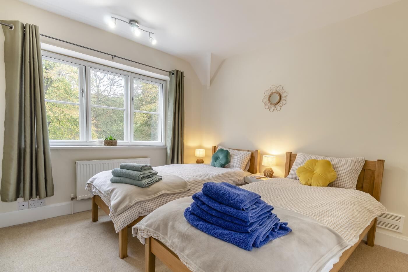 Ein Schlafzimmer mit zwei Betten, einem Fenster mit Vorhängen, Nachttischlampen und einer Heizung.