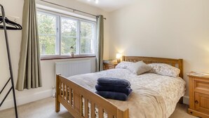 A bedroom with a wooden bed, a nightstand, a window with curtains, and a radiator. - 3 Bed in Guist (oc-h33647) (Guist)