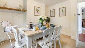 A dining area with a table set for four, chairs, a coffee maker, and a vase with flowers. - 3 Bed in Guist (oc-h33647) (Guist)