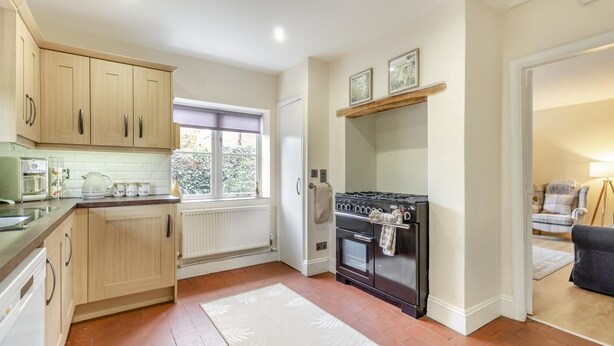 A compact kitchen with wooden cabinets, a built-in oven, and a window providing natural light. - 3 Bed in Guist (oc-h33647) (Guist)