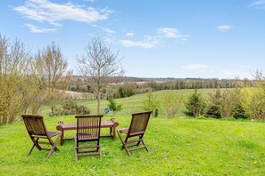 A picnic setup with a table and chairs in a grassy field with a view of a hilly landscape. - 1 Bed in Milton Abbas (oc-l35018) (Milton Abbas)