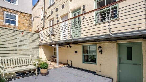 A building with a green door, a bench, and a small garden area. - 2 Bed in Whitby (oc-m32879) (Whitby)