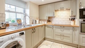 A modern kitchen with a washing machine, a sink, and a window providing natural light. - 2 Bed in Whitby (oc-m32879) (Whitby)