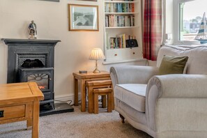 Ein gemütliches Wohnzimmer mit Kamin, Bücherregal, Lampe und Sofa.