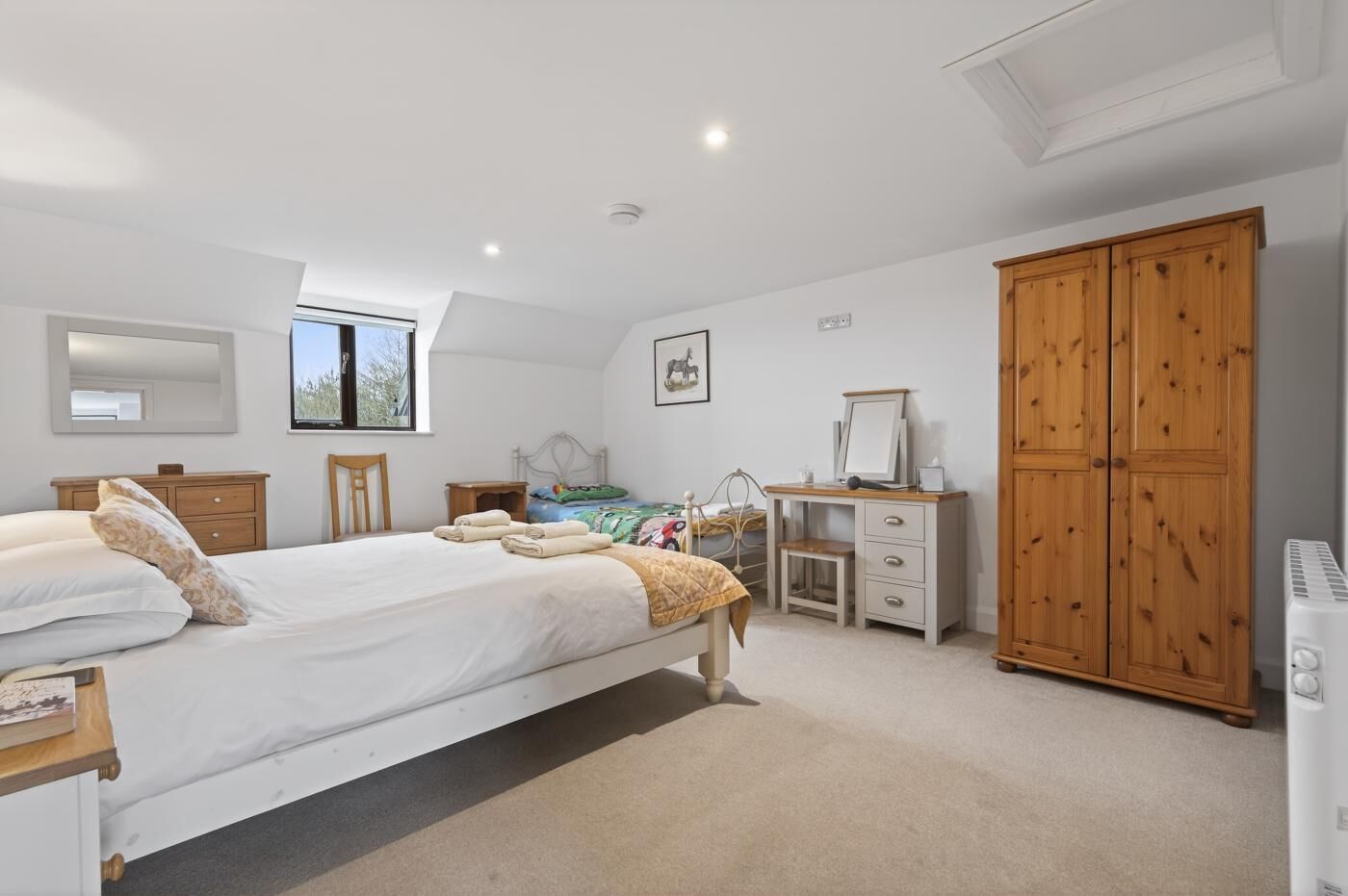 A bedroom with a bed, bedside tables, a desk, a wardrobe, and a radiator.