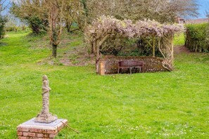 A garden with a statue, a wooden pergola, and a bench. - 1 Bed in Milton Abbas (oc-o35015) (Milton Abbas)