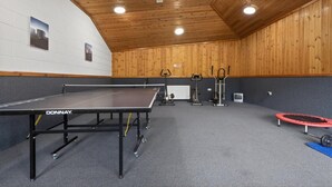 Ein Sportbereich mit Tischtennisplatte, Fitnessgeräten und Trampolin.