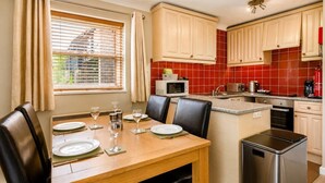 A kitchen with a dining area, featuring a table set for four, a microwave, a toaster, and a stainless steel dishwasher. - 1 Bed in Barnham Broom (oc-p42617) (Barnham Broom)