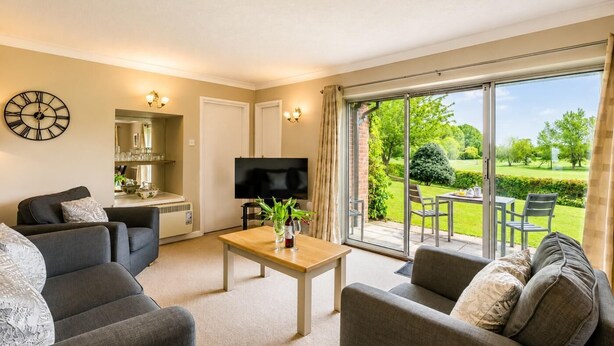 A living room with a sofa, a coffee table, and a television. There is a sliding glass door leading to a garden. - 1 Bed in Barnham Broom (oc-p42617) (Barnham Broom)